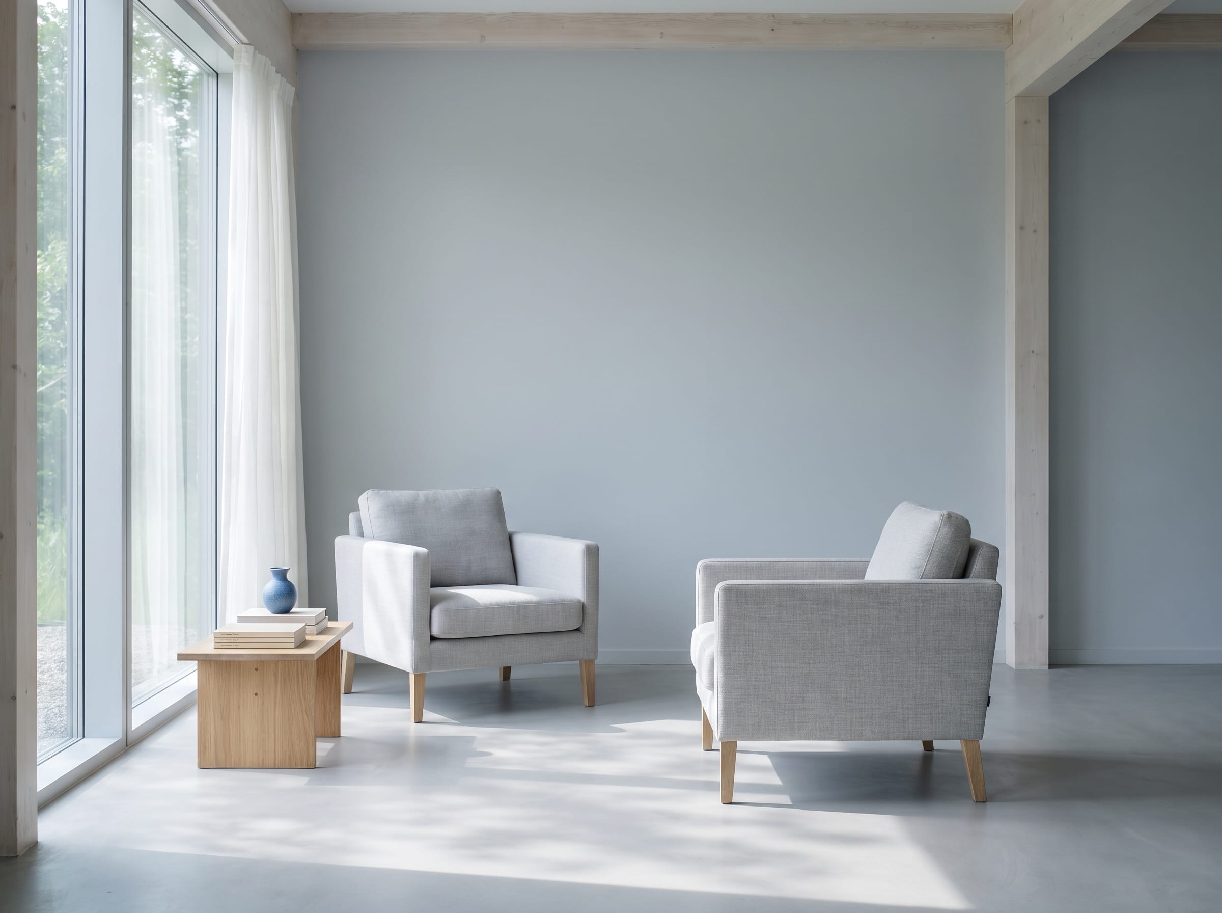 Two chairs and a side table by a daylight window in a calm consultation room
